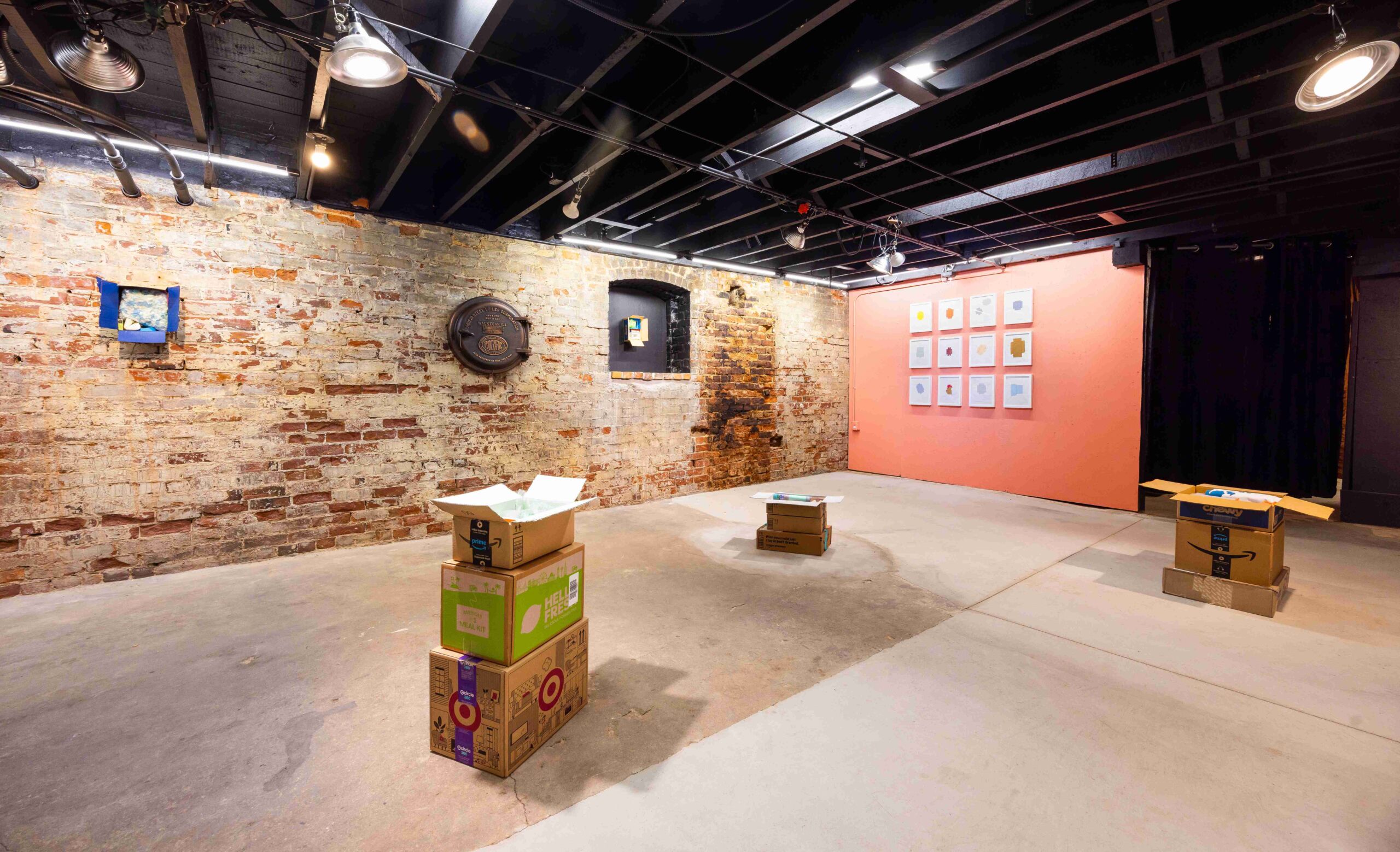 Industrial gallery space with exposed brick walls and concrete floors displaying sculptures and drawings